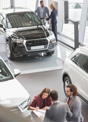 Car sales people and customers in car dealership showroom